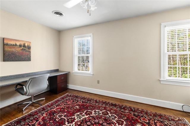 office area with dark wood-style floors, visible vents, plenty of natural light, and baseboards