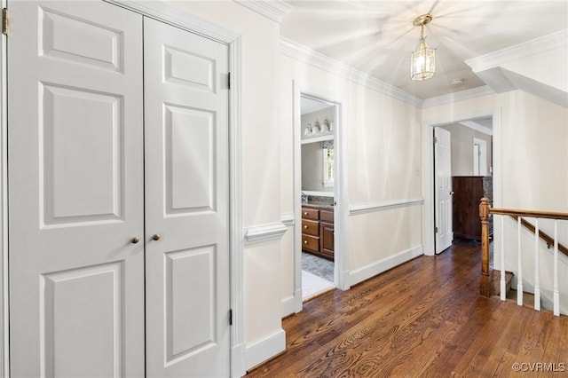 hall with baseboards, dark wood finished floors, an upstairs landing, and crown molding