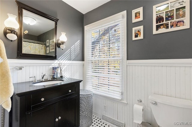 full bathroom featuring a wainscoted wall, vanity, and toilet