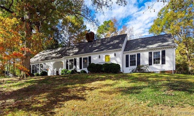 cape cod house with a chimney and a front yard