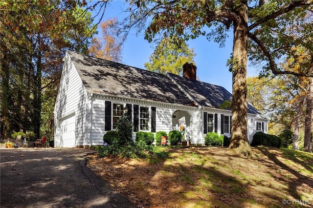 view of front of home featuring a garage, driveway, and a chimney