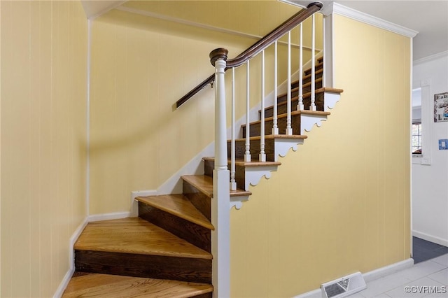 staircase featuring baseboards, visible vents, and crown molding