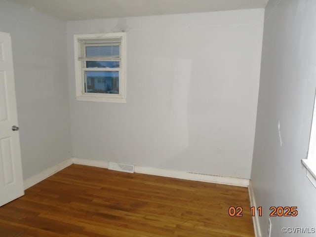 unfurnished room with wood finished floors, visible vents, and baseboards