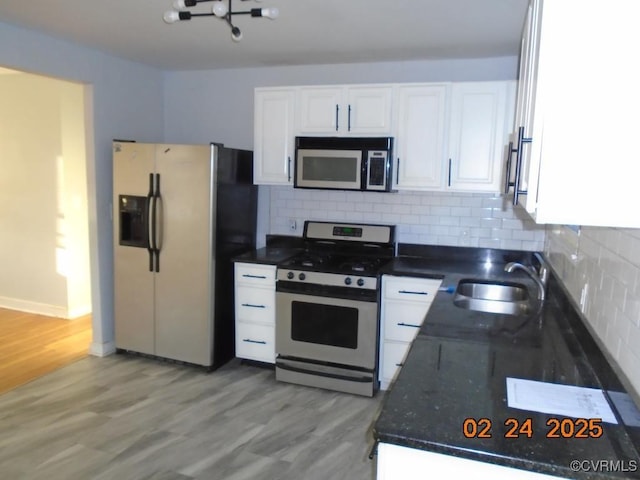 kitchen featuring tasteful backsplash, light wood-style flooring, appliances with stainless steel finishes, white cabinetry, and a sink