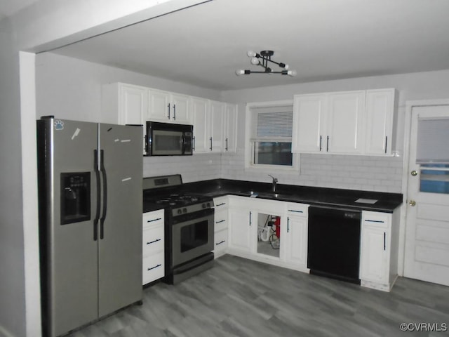 kitchen featuring black appliances, dark countertops, a sink, and white cabinets