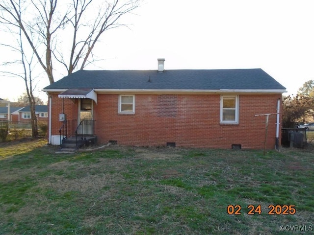 rear view of house featuring fence, a lawn, and brick siding