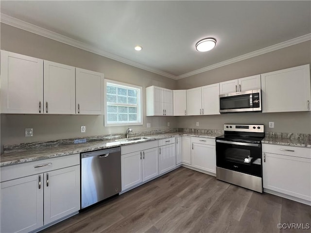 kitchen with stainless steel appliances, ornamental molding, dark wood finished floors, and white cabinetry