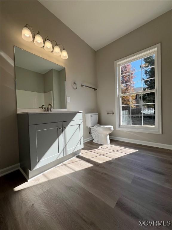 bathroom with toilet, baseboards, wood finished floors, and vanity