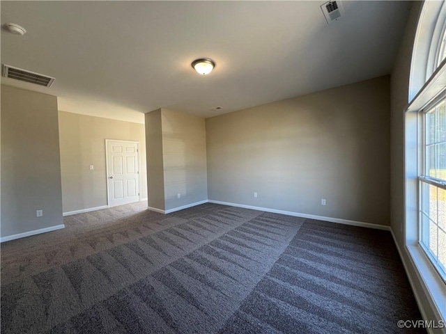 unfurnished room with baseboards, visible vents, and dark colored carpet