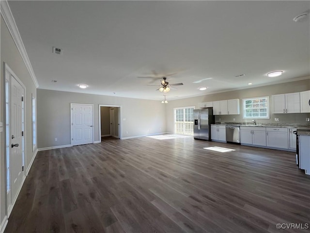 kitchen with stainless steel appliances, open floor plan, white cabinets, and crown molding