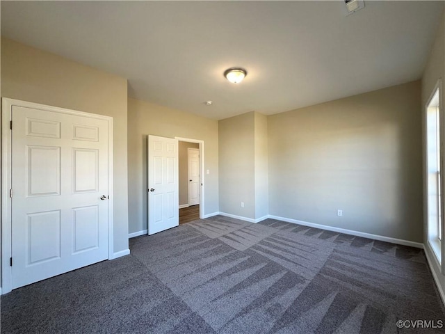 unfurnished bedroom with baseboards and dark colored carpet