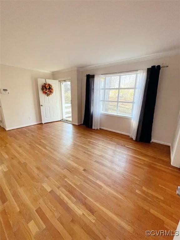 unfurnished living room featuring light wood-style floors, ornamental molding, and baseboards