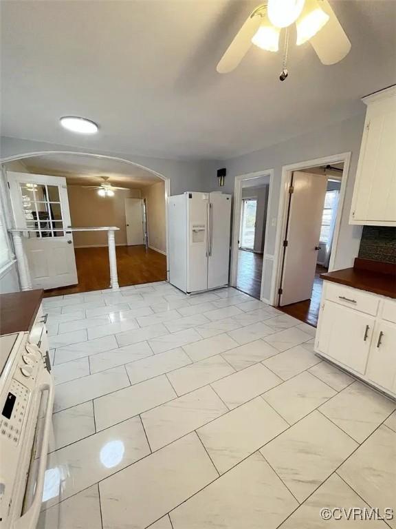 kitchen with arched walkways, dark countertops, washer / clothes dryer, ceiling fan, and white fridge with ice dispenser