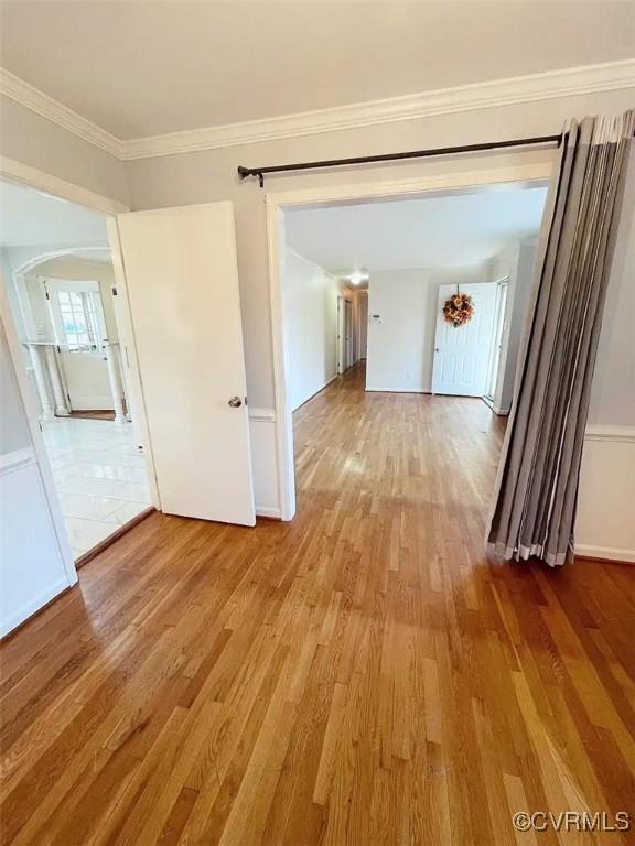 hallway with arched walkways, crown molding, and wood finished floors