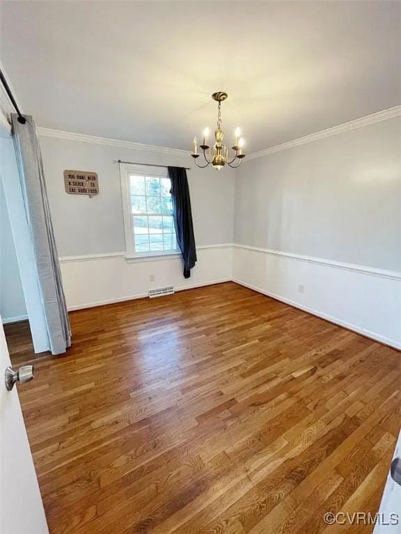 unfurnished dining area with wood finished floors, visible vents, baseboards, ornamental molding, and an inviting chandelier