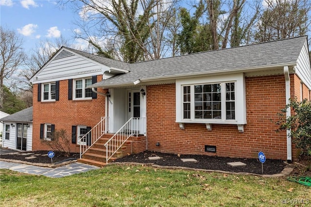 tri-level home featuring a shingled roof, a front lawn, brick siding, and crawl space