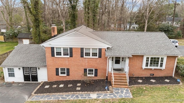 split level home with brick siding, roof with shingles, and a chimney