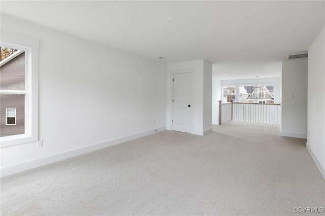 spare room featuring light carpet, visible vents, and baseboards