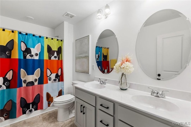 bathroom featuring toilet, double vanity, a sink, and visible vents