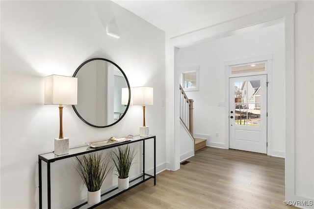 foyer entrance with visible vents, light wood-style flooring, baseboards, and stairs