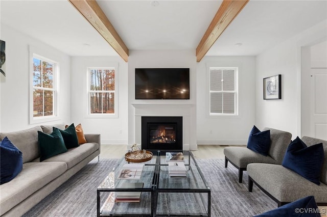 living room with wood finished floors, beamed ceiling, and a glass covered fireplace