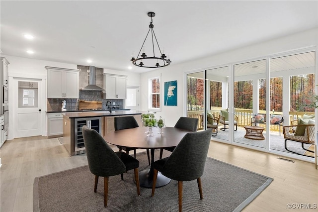 dining space featuring light wood-style floors, wine cooler, visible vents, and recessed lighting