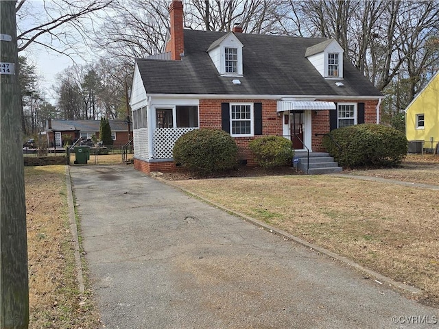 cape cod home with brick siding, a front lawn, and a chimney