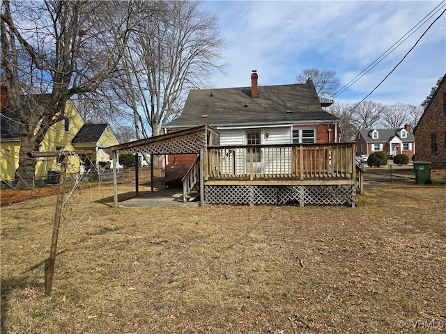 back of property featuring a deck, a patio, brick siding, fence, and a chimney