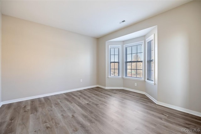 spare room with visible vents, baseboards, and wood finished floors