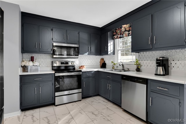 kitchen featuring marble finish floor, stainless steel appliances, a sink, and light countertops