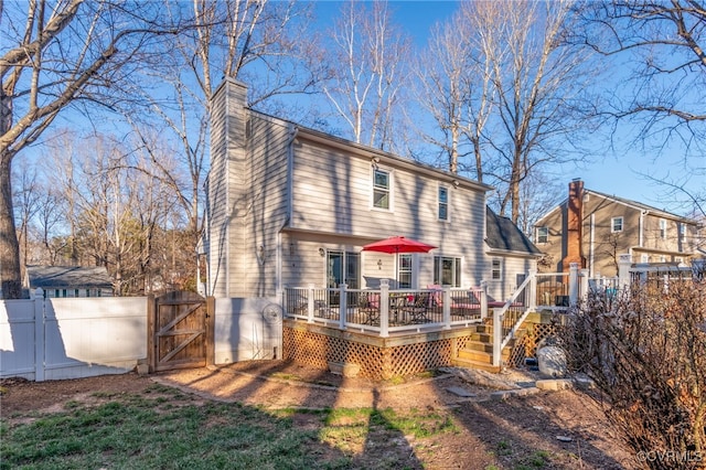 rear view of property featuring a deck, a gate, fence, and a chimney