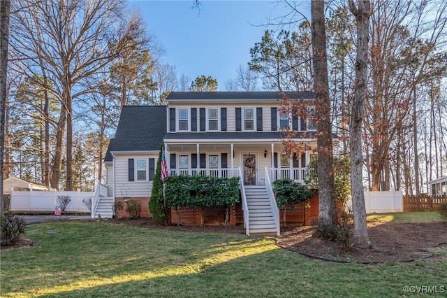 view of front facade featuring a porch, fence, stairway, and a front lawn