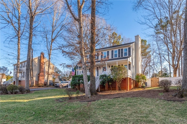 exterior space featuring a yard, a chimney, covered porch, fence, and stairs