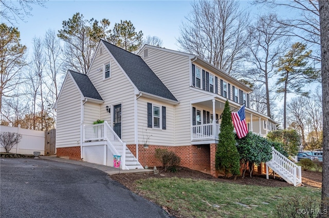 view of front of house with a shingled roof, a porch, fence, and stairs