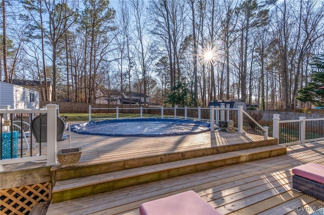 deck with a fenced backyard, a shed, a fenced in pool, and an outbuilding