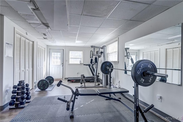 exercise room with a drop ceiling, baseboards, and wood finished floors