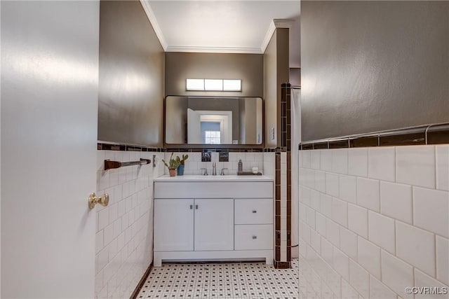 bathroom featuring a wainscoted wall, tile patterned floors, crown molding, vanity, and tile walls