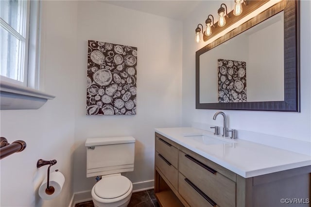 bathroom featuring baseboards, vanity, and toilet