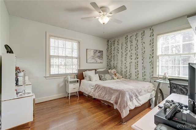 bedroom with ceiling fan, light wood finished floors, multiple windows, and baseboards