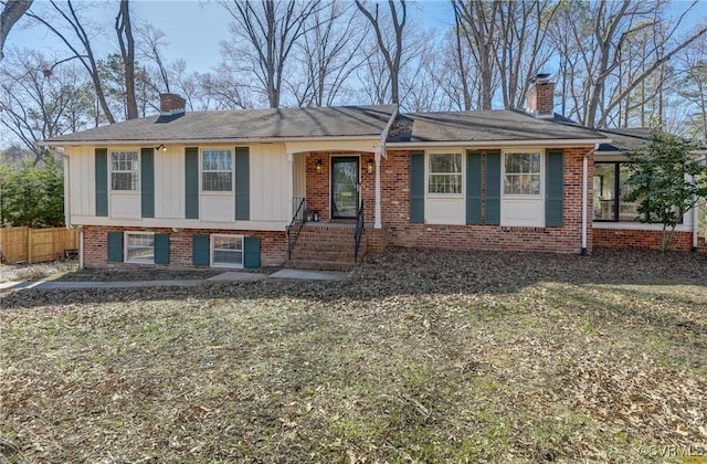 view of front of house featuring brick siding, fence, and a chimney