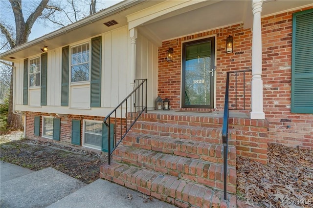 doorway to property featuring a porch and brick siding