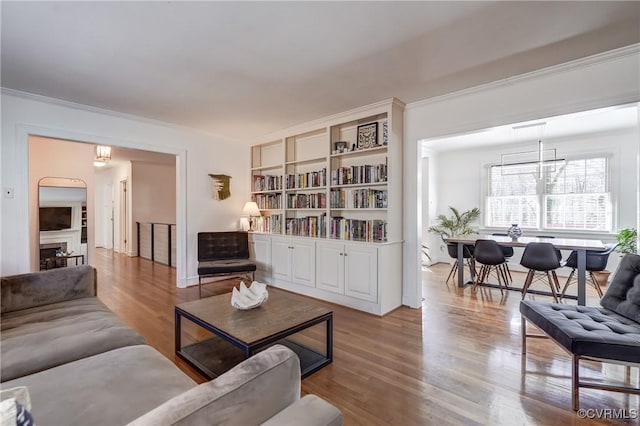 living area featuring ornamental molding, a fireplace, and wood finished floors