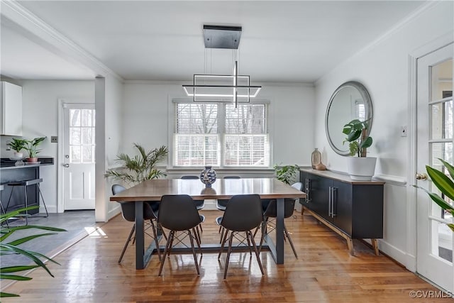 dining area featuring ornamental molding, light wood-type flooring, and baseboards