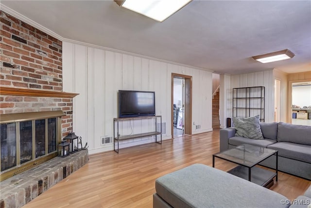 living area featuring visible vents, a fireplace, stairway, and wood finished floors