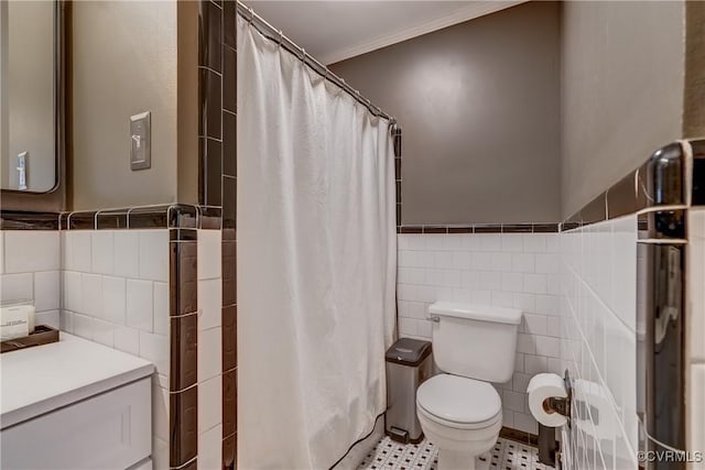 bathroom with a wainscoted wall, tile walls, and toilet