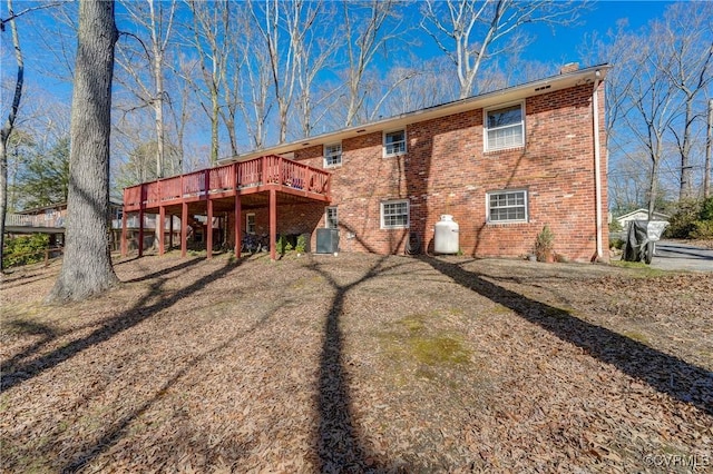 rear view of house with central air condition unit, a chimney, a deck, and brick siding