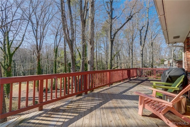 wooden deck with a forest view and a grill