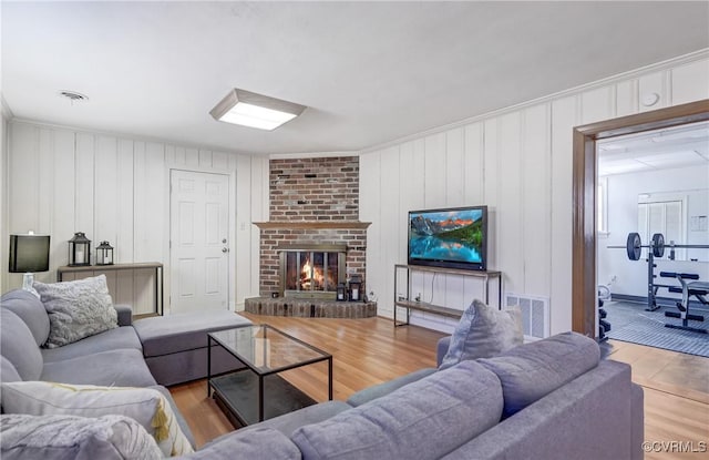 living room featuring a brick fireplace, wood finished floors, and visible vents