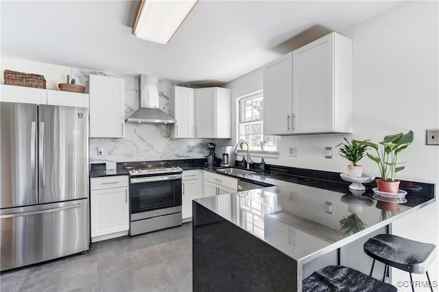 kitchen featuring white cabinets, appliances with stainless steel finishes, a peninsula, wall chimney range hood, and a sink