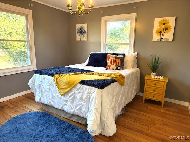 bedroom with hardwood / wood-style flooring, baseboards, ornamental molding, and a chandelier